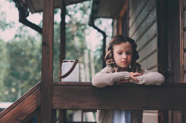 Девочка с подсвечником отдыхает вечером в уютном загородном доме. Ребёнок проводит летние каникулы в бревенчатой хижине в лесу — стоковое фото