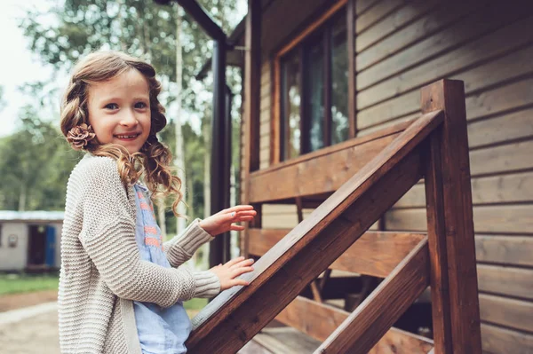Kid girl playing at wooden cabin in the woods. Child spending summer vacation outdoor at country house — Stock Image Kid girl playing at wooden cabin in the woods. Child spending summer vacation outdoor at country house Stock Picture