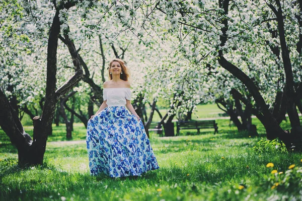Krásná mladá žena v květinové maxi sukni chůzi na jaře — Stock fotografie