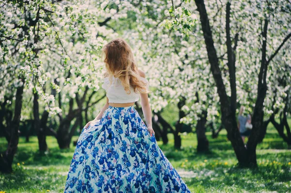 Hermosa joven en falda maxi floral caminando en primavera —  Fotos de Stock