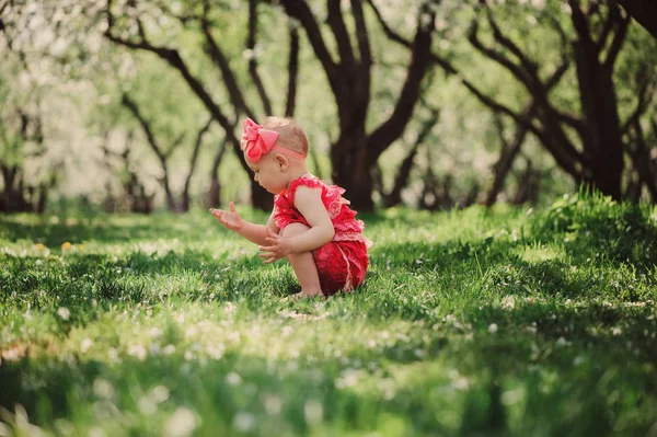 Cute happy baby girl in funny pink romper walking outdoor in spring garden. Happy childhood concept — Stock Photo, Image