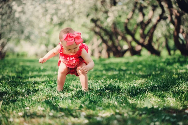 Aranyos boldog baba lány séta vicces rózsaszín romper szabadtéri tavaszi kertben. Boldog gyermekkor fogalma — Stock Fotó