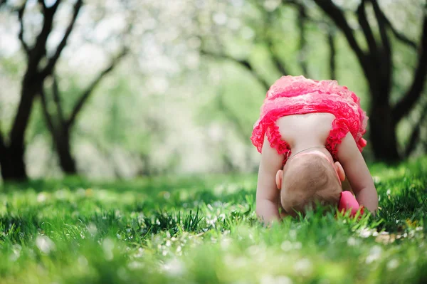 Linda niña feliz en divertido rosa mameluco caminando al aire libre en el jardín de primavera. Concepto de infancia feliz —  Fotos de Stock