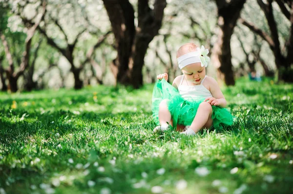Bonito feliz bebê menina em verde tutu saia andando ao ar livre no jardim de primavera. Conceito de infância feliz — Fotografia de Stock