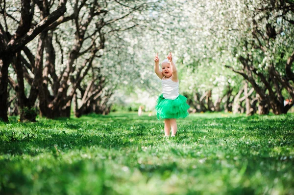 Cute happy baby dziewczyna w zielonej tutu spódnica spaceru odkryty w spring garden. Koncepcja szczęśliwe dzieciństwo — Zdjęcie stockowe