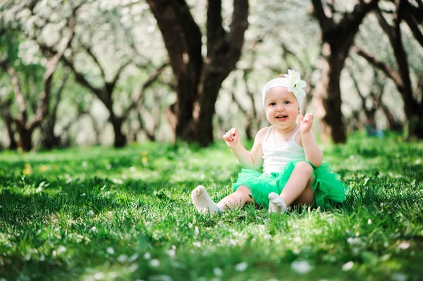 Cute happy baby dziewczyna w zielonej tutu spódnica spaceru odkryty w spring garden. Koncepcja szczęśliwe dzieciństwo — Zdjęcie stockowe