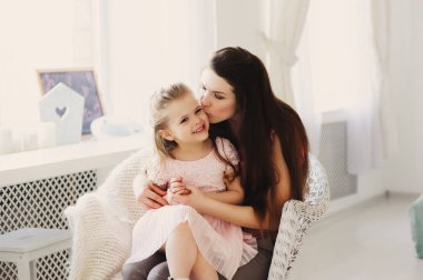 mutlu bir aile evde sandalyede oturuyor. Rahat yaşam tarzı yakalama anne ve yürümeye başlayan çocuk kızı