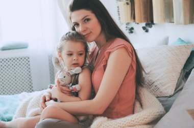 mutlu bir aile evde oynamak. Rahatlatıcı ve having fun yatakta sıcak hafta sonu sabah anne ve yürümeye başlayan çocuk kızı