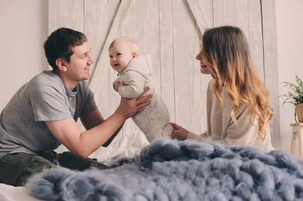 Gelukkige familie thuis speelt op het bed. Vangst van de levensstijl van moeder, vader en baby in moderne Scandinavische interieur — Stockfoto