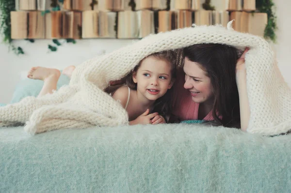 Familia feliz jugando en casa. Madre e hija pequeña relajándose y divirtiéndose en la cama en la acogedora mañana de fin de semana — Foto de Stock