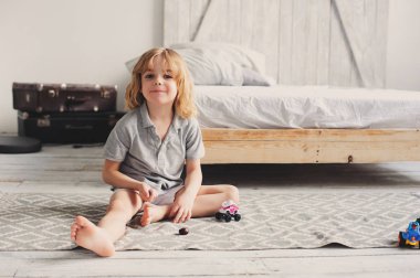 evde oyuncak arabalar ile sabah oynarken mutlu çocuk çocuk. Yatak odasında rahat yaşam tarzı