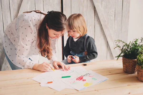 Madre enseñando a niño a dibujar con lápices en casa. Familia pasar tiempo juntos — Foto de Stock