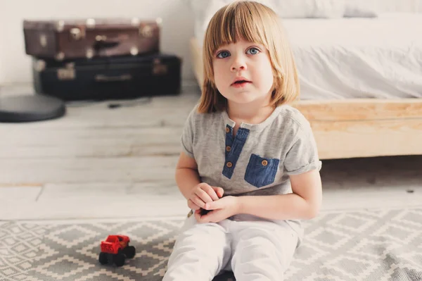 Niño feliz jugando con coches de juguete en casa por la mañana. Estilo de vida casual en el dormitorio — Foto de Stock