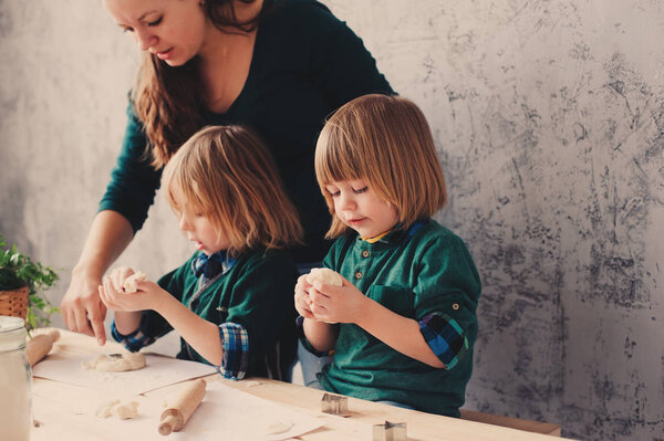 mother cooking with kids in kitchen. Toddler siblings baking together and playing with pastry at home in weekend morning