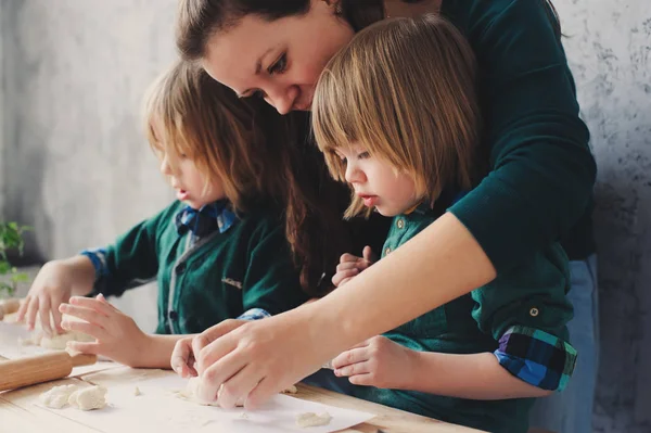 Mamma cucina con bambini in cucina. I fratelli più piccoli cuociono insieme e giocano con la pasticceria a casa nel fine settimana mattina — Foto Stock