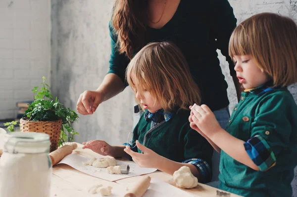 Madre cocinando con niños en la cocina. Hermanos pequeños horneando juntos y jugando con pastelería en casa en la mañana del fin de semana — Foto de Stock