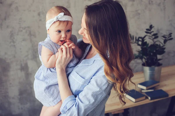 Gelukkig moeder en baby spelen thuis in de slaapkamer. Gezellige familie levensstijl in moderne Scandinavische interieur. — Stockfoto