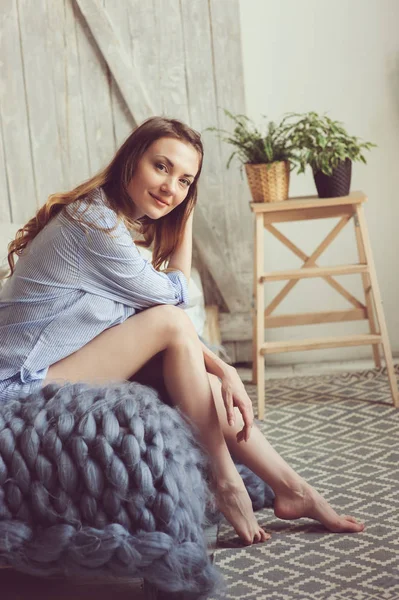 Young woman in pajama wake up in the morning in cozy scandinavian bedroom and sitting on bed with white bedlinen. Casual lifestyle in modern interior — Stock Photo, Image