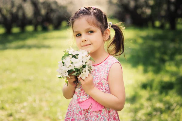 Spring closeup outdoor portrait of adorable kid girl. Spending spring holidays in beautiful blooming garden — Stock Photo, Image