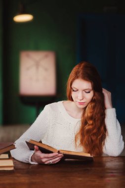 genç güzel kızıl saçlı öğrenci kadın okuma kitabı Üniversite Kütüphanesi, akşamları öğrenme