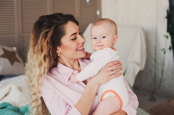 Familia feliz en casa. Madre sosteniendo bebé hijo en el dormitorio en la mañana de fin de semana acogedor —  Fotos de Stock