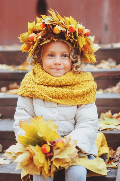 Roztomilý rozkošný batole dívka vertikální portrét s kytice podzimní listí a věnec chůzi venkovní v parku nebo v lese, na sobě teplé pletené žluté snood — Stock fotografie