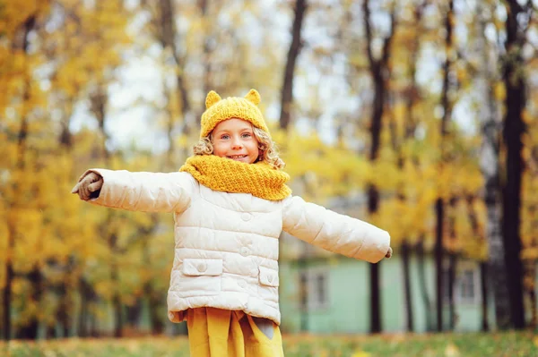 Grappige herfst portret van gelukkig peuter meisje lopen buiten in stijlvolle gebreide oranje haarband — Stockfoto