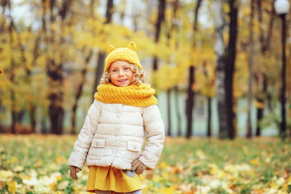 Divertente ritratto autunnale di felice bambina che cammina all'aperto in elegante snood arancione lavorato a maglia — Foto Stock