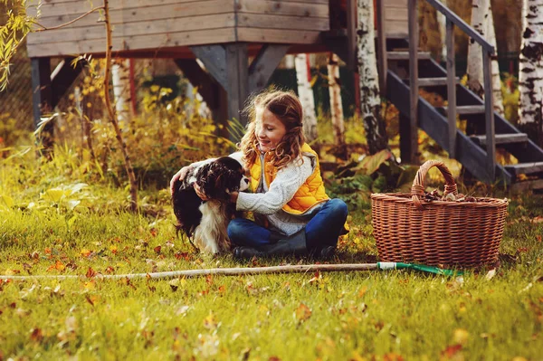 Lyckligt barn flicka som leker lite trädgårdsmästare på hösten och plocka bladen i korgen. Trädgård säsongsarbete. — Stockfoto