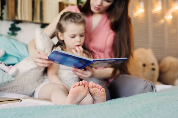 Мать читает книгу дочке малыша в спальне для спокойной ночи. Повседневный образ жизни захват счастливой семьи дома — стоковое фото