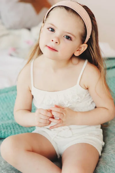 Retrato interior de niña triste de 5 años sentada en la cama en pijama — Foto de Stock