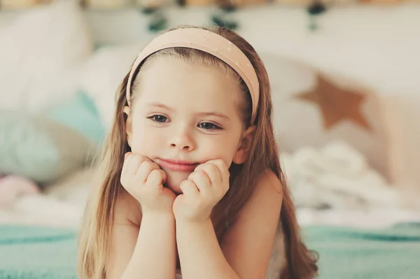 Indoor portrait of sad 5 years old child girl sitting on bed in pajama — Stock Photo, Image