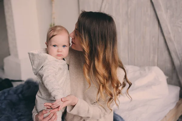 Boldog anya és 8 hónapos baba, játék, és pihentető hálószobás otthon reggel. Hangulatos családi életmód-modern skandináv belső. — Stock Fotó