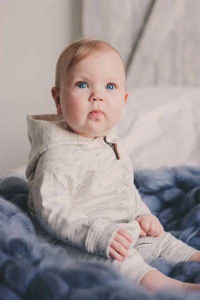 Retrato de lindo bebé de 8 meses sentado en la cama en la manta de punto en casa —  Fotos de Stock