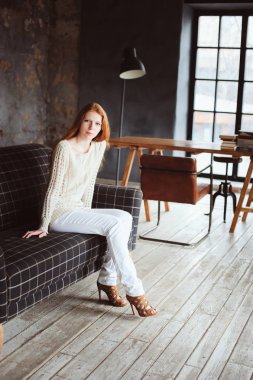 genç güzel kızıl saçlı kadın rahatlatıcı akşam ve kanepede kitap okuma sonbahar rahat evde