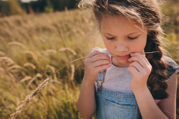 Bambino felice ragazza in jeans nel complesso giocando sul campo di sole, stile di vita all'aperto estivo, umore accogliente — Foto Stock