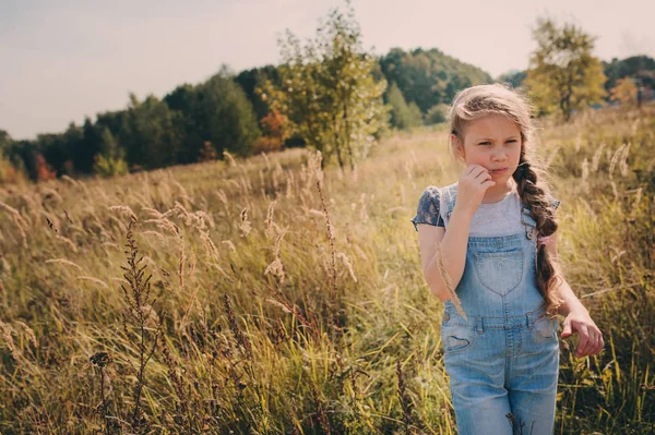 Niña feliz en jeans en general jugando en el campo soleado, estilo de vida al aire libre de verano, ambiente acogedor —  Fotos de Stock