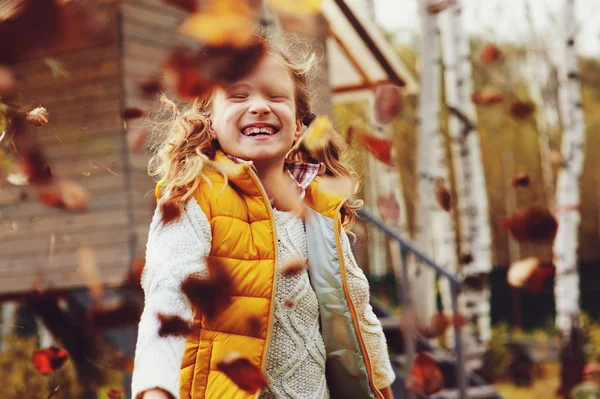 Szczęśliwe dziecko dziewczynka gra Mały ogrodnik w jesieni i zbieranie liści do koszyka. Sezonowej pracy w ogrodzie. Podwórku, czyszczenie. — Zdjęcie stockowe