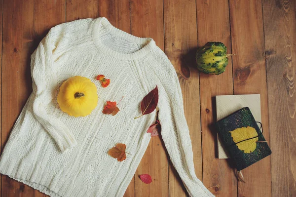 Cozy knitted sweater with pumpkin and fall leaves on wooden background — Stock Photo, Image