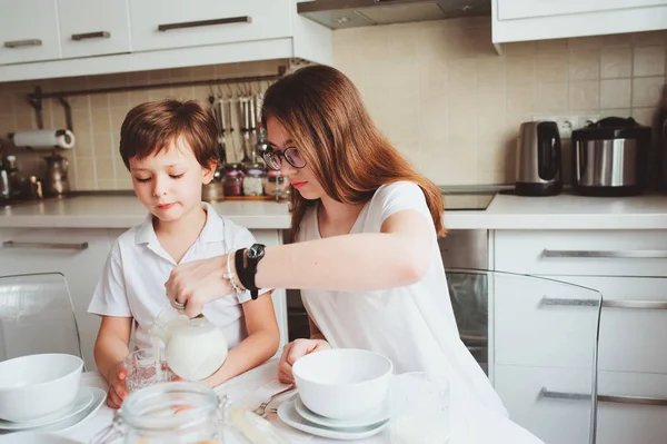 동생과 청소년 자매 현대 백색 부엌에서 집에서 아침 식사와 스낵을 먹는 아이. 실제 인테리어에 캐주얼 라이프 스타일 — 스톡 사진