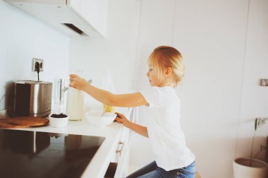 modern beyaz mutfak, sabahları rahat yaşam tarzı çocuk kızı evde kahvaltı yapıyor anne