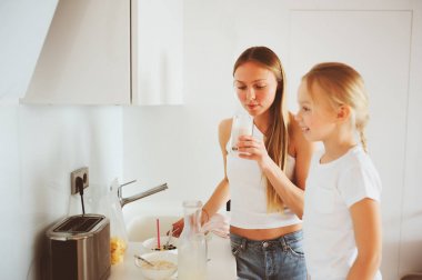 modern beyaz mutfak, sabahları rahat yaşam tarzı çocuk kızı evde kahvaltı yapıyor anne