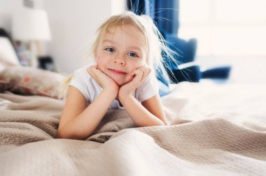 Pijama yatakta oturup şirin mutlu bebek kız. Evde, gündelik yaşam tarzı yakalama oynayan çocuk.