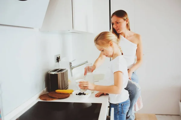 Mãe tomando café da manhã com filha criança em casa na cozinha branca moderna, estilo de vida acolhedor pela manhã — Fotografia de Stock