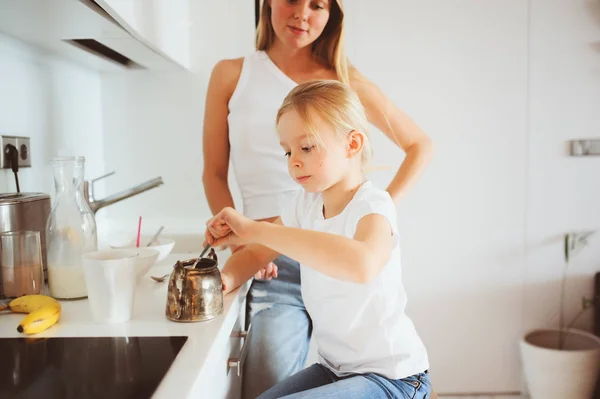 Mãe tomando café da manhã com filha criança em casa na cozinha branca moderna, estilo de vida acolhedor pela manhã — Fotografia de Stock