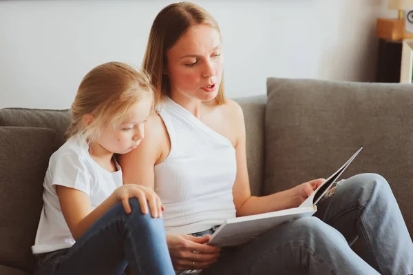 Mother reading book to toddler daughter in bedroom for good night. Casual lifestyle capture of happy family at home — Stock Photo, Image