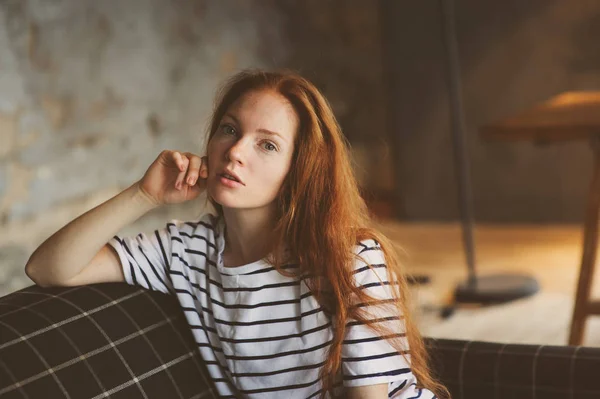 Retrato de joven hermosa pelirroja que se relaja en casa en el otoño o invierno noche acogedora en el sofá — Foto de Stock