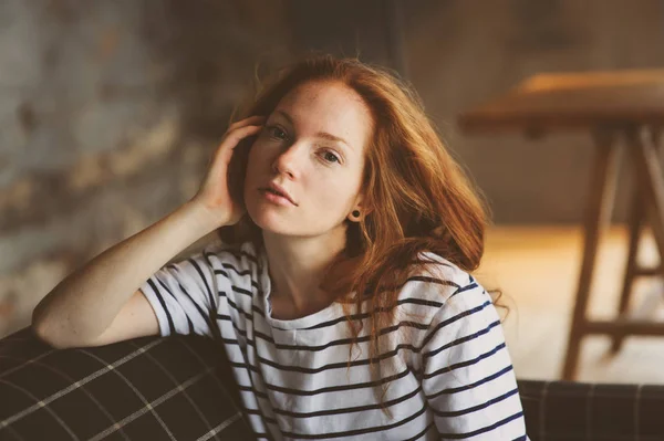 Retrato de joven hermosa pelirroja que se relaja en casa en el otoño o invierno noche acogedora en el sofá —  Fotos de Stock