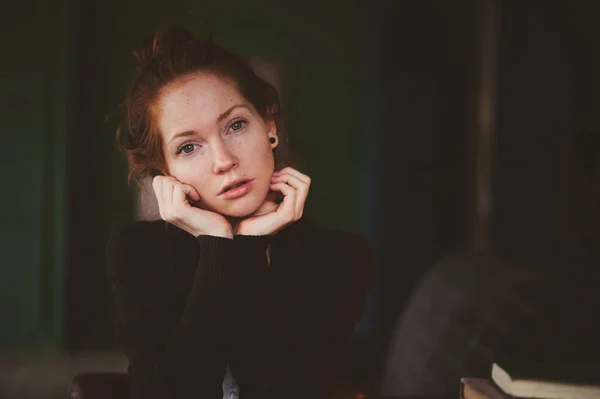 Close up indoor portrait of beautiful thoughtful redhead woman with freckles in dark interior — Stock Photo, Image