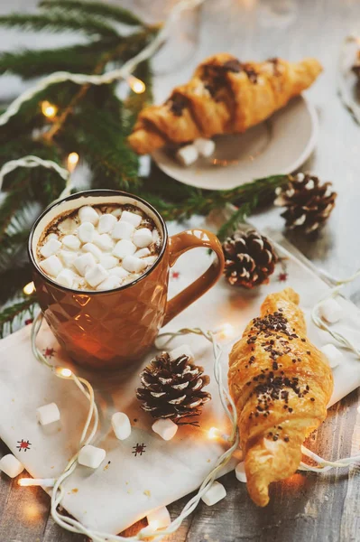 Gorące kakao z pianki i rogalika na rustykalne drewniany stół z Boże Narodzenie światła. Koncepcja domu przytulne zimowe — Zdjęcie stockowe